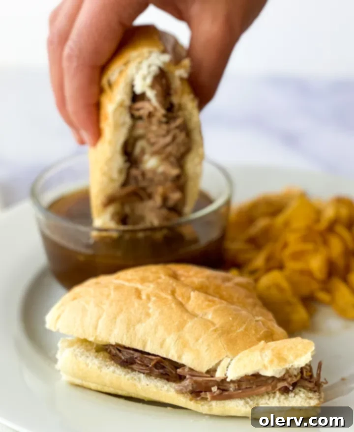 Ultimate Slow Cooker French Dip Sandwiches 3 Close-up of shredded, tender beef from the slow cooker, glistening with rich juices, ready to be assembled into French Dip sandwiches.