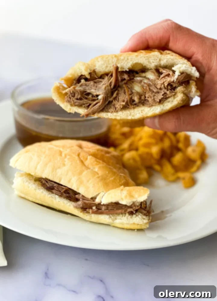 Ultimate Slow Cooker French Dip Sandwiches 5 A small white bowl filled with rich, dark au jus, emitting steam, perfect for dipping tender beef French Dip sandwiches.