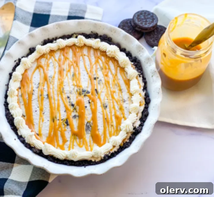 Decadent Salted Caramel Oreo Pie 2 A slice of creamy Salted Caramel Oreo Pie with a generous drizzle of caramel sauce and cookie crumbs.