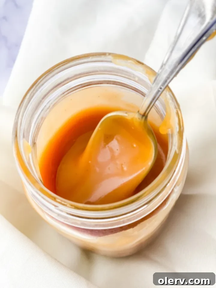 Irresistible Homemade Salted Caramel 3 Close-up of a spoon drizzling rich homemade caramel sauce.