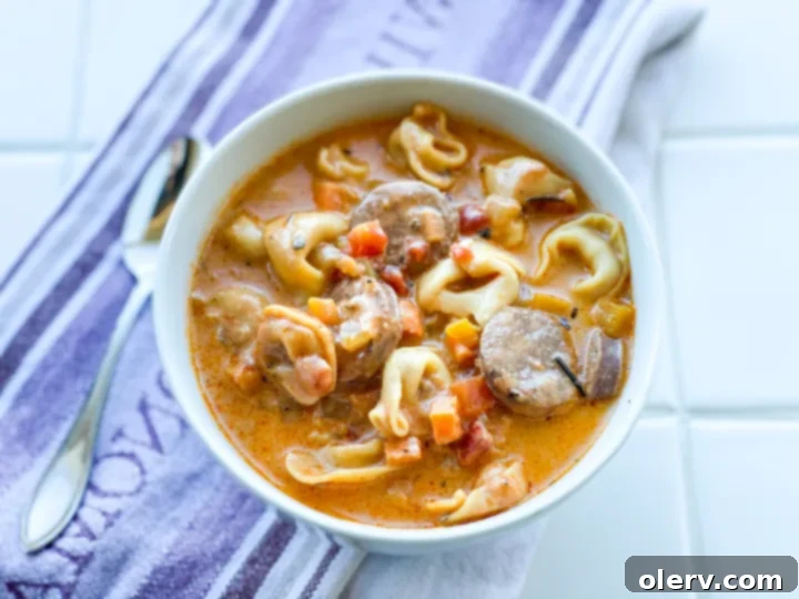 Hearty Sausage and Tortellini Soup 2 A steaming bowl of creamy sausage and tortellini soup, garnished with fresh herbs.