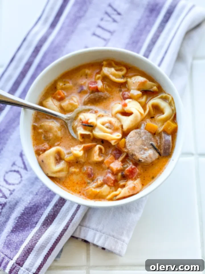 Hearty Sausage and Tortellini Soup 4 Sausage and diced vegetables cooking in a large pot for the soup.