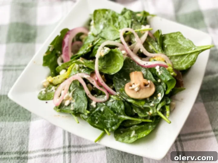 Effortless Marinated Spinach Delight 2 Easy Marinated Spinach Salad with candied pecans and bacon bits, served in a white bowl, ready to eat.