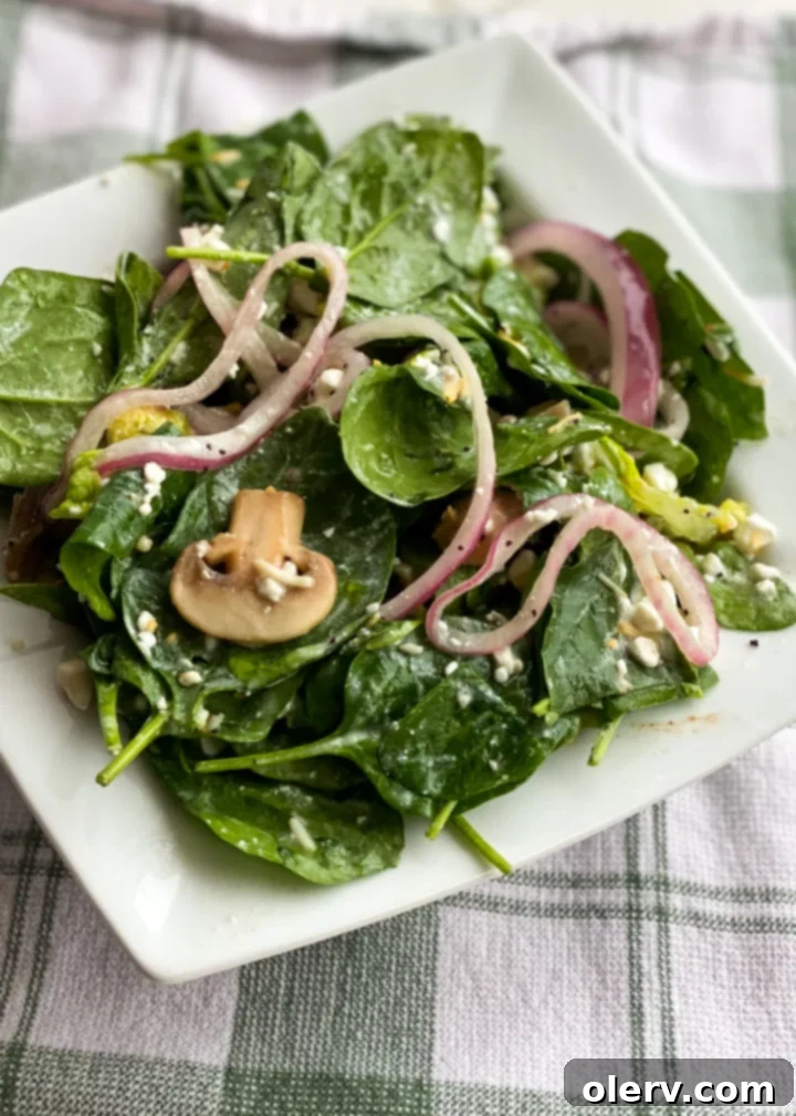 Effortless Marinated Spinach Delight 6 A spoonful of the marinated spinach salad, showing the mixture of greens, cheese, mushrooms, and dressing.