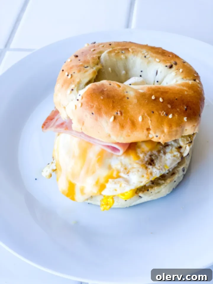 Prepared ham, egg, and cheese bagel sandwich with avocado ingredients displayed.
