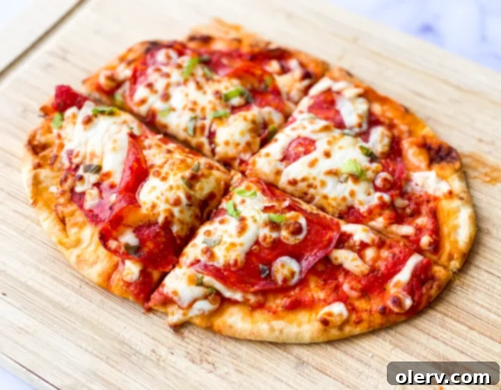 Crispy Air Fryer Pizza 3 A top-down view of a personal air fryer pizza with sauce, cheese, and pepperoni being prepared on a wooden cutting board.