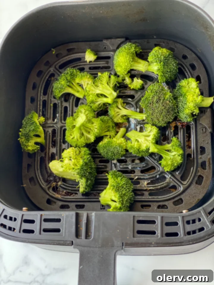 Easy Air Fryer Salmon and Veggies 6 Salmon fillets cooking in an air fryer basket, perfectly browning