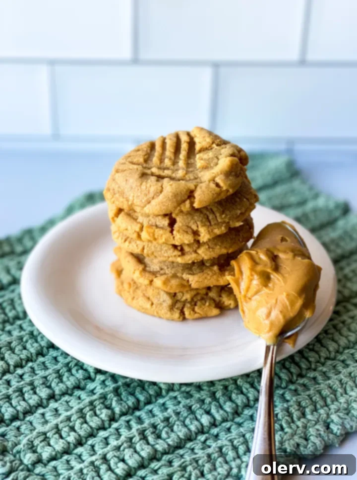 Effortless Three Ingredient Peanut Butter Cookies 2 Freshly baked 3-ingredient peanut butter cookies on a cooling rack, showcasing their classic fork marks and golden brown edges.