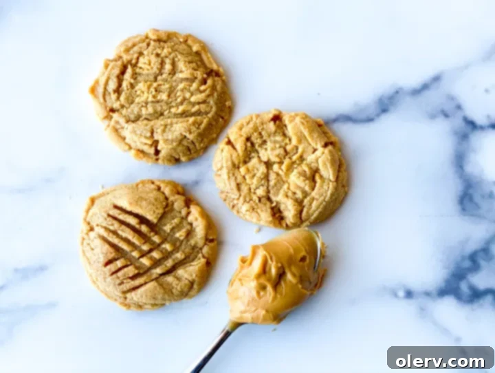 Effortless Three Ingredient Peanut Butter Cookies 4 Close-up of baked 3-ingredient peanut butter cookies with crisscross fork patterns, cooling on a wire rack.