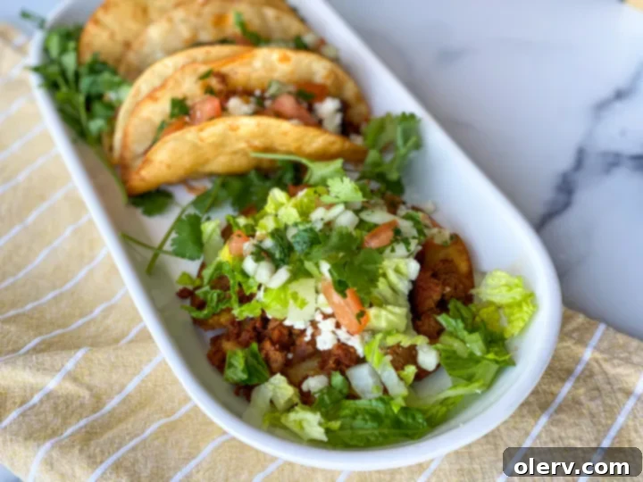 Close-up of corn tortillas frying in hot oil, being folded into a taco shape with tongs.