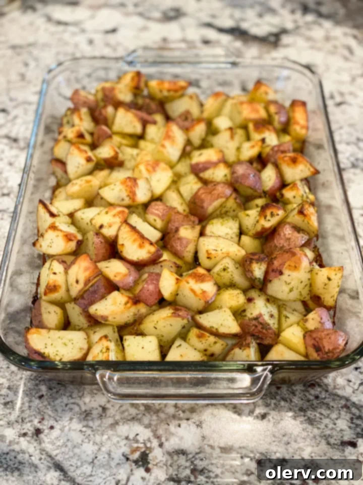 Crispy Garlic Roasted Potatoes 5 Raw cubed potatoes tossed with olive oil, garlic, and herbs in a bowl.