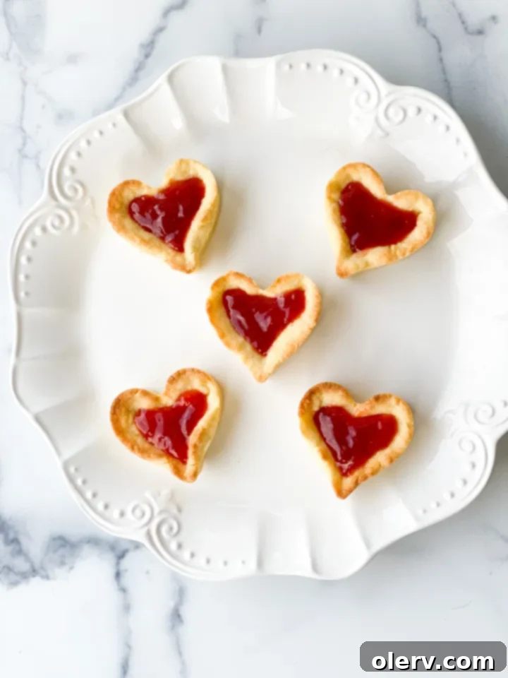 Sweet Strawberry Tartlets 5 A bowl of glossy strawberry jam, ready to be spread into the baked mini tart crusts, highlighting its rich color and texture.
