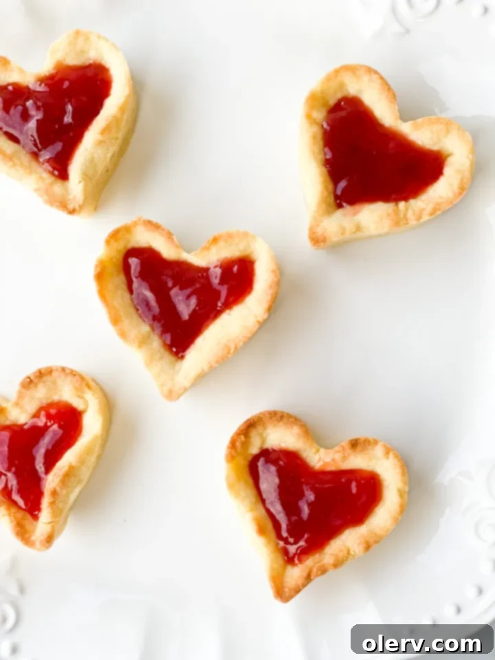 Sweet Strawberry Tartlets 7 A close-up of a single Sweet Mini Strawberry Tart, showcasing its perfectly crimped crust, shiny jam filling, and tender texture, inviting a taste.