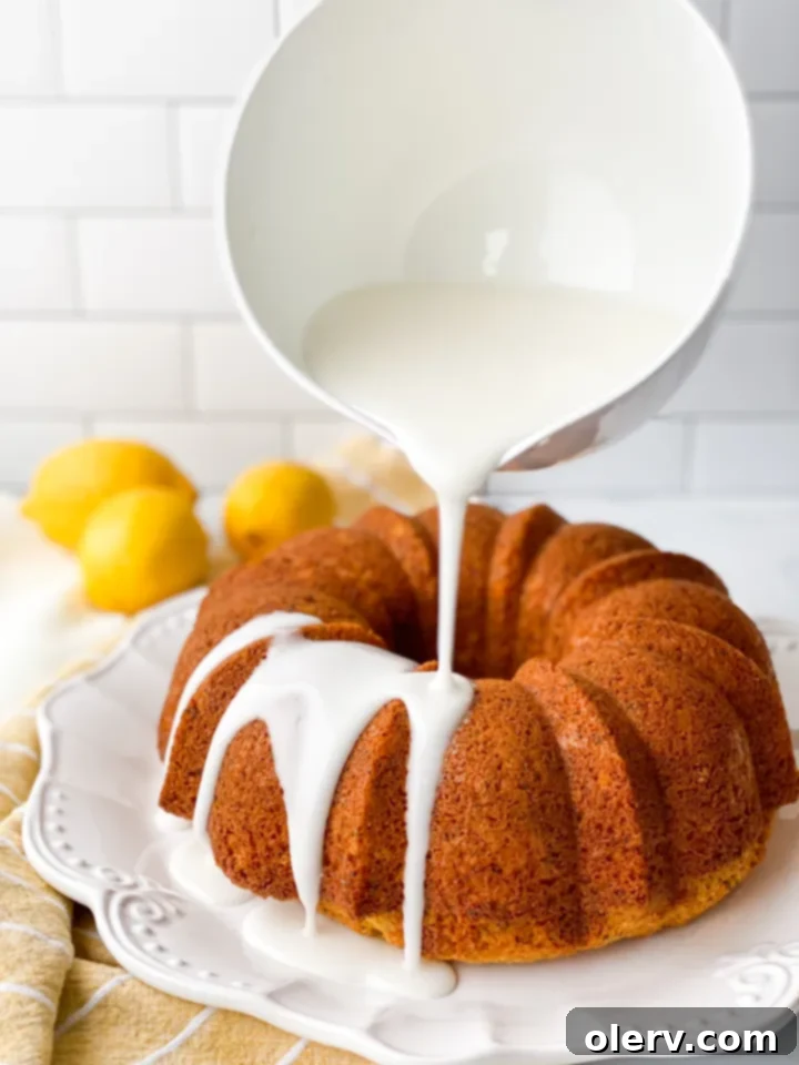 Limon Soslu Haşhaşlı Kek 3 A close-up of a slice of Poppy Seed Bundt Cake, revealing its moist crumb and visible poppy seeds, with a generous coating of lemon glaze, resting on a white plate.