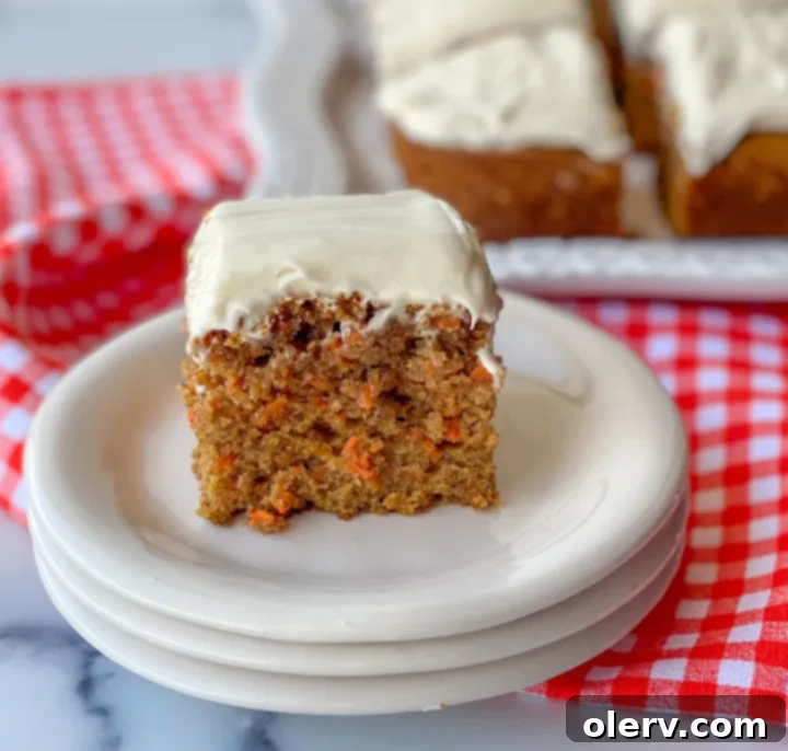 No-Fuss Carrot Cake Bars 6 A square of frosted carrot cake bar, freshly cut and ready to be served, showing its moist interior.