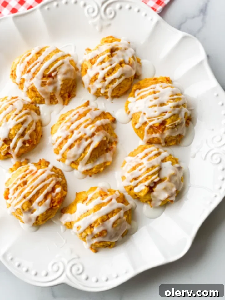 Chewy Spiced Carrot Cake Cookies 4 A hand holding a single carrot cake cookie with icing, ready to be enjoyed.