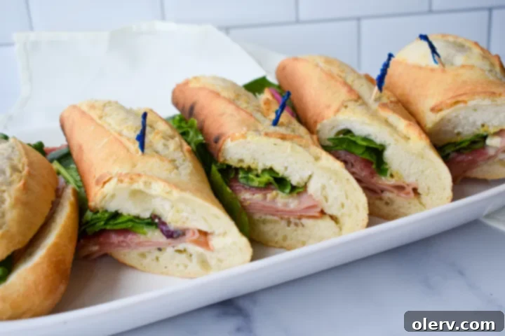 Artisan Baguette 2 A perfectly crafted French baguette sandwich, cut to reveal layers of ham, salami, melted brie, and fresh greens, served on a rustic wooden board.