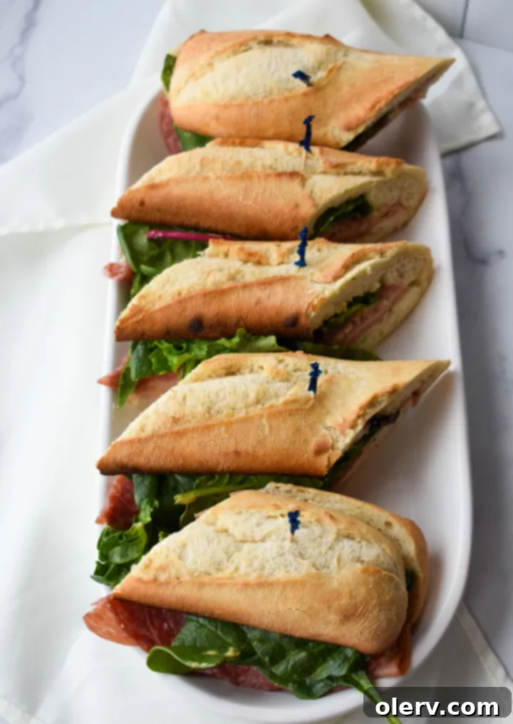 Artisan Baguette 4 The impressive French baguette sandwich, showcasing its vibrant layers of ingredients, cut into several portions for serving.
