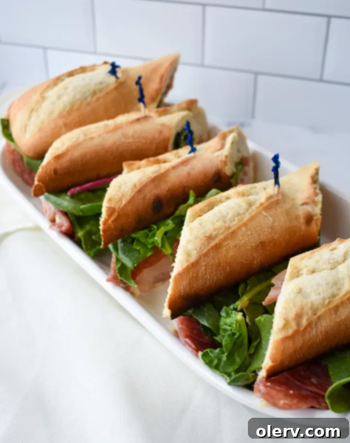 Artisan Baguette 7 Two generous halves of the exquisite French baguette sandwich, beautifully arranged and garnished with fresh greens, ready to be enjoyed.