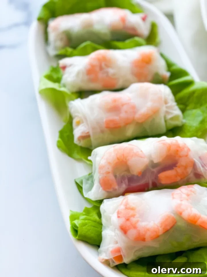 Crispy Homemade Spring Rolls 9 Freshly rolled spring rolls arranged on a wooden board, ready to be served or stored