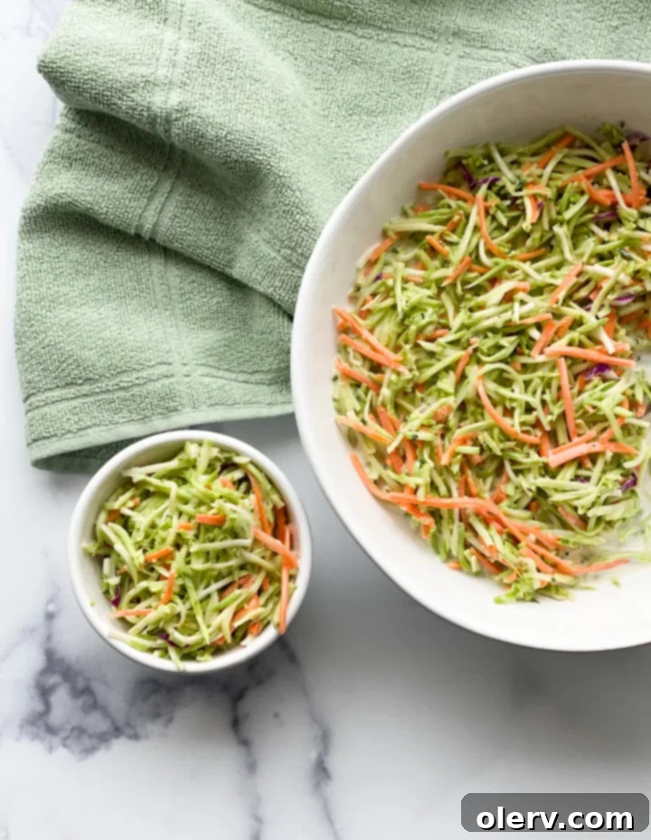 Zesty Broccoli Power Slaw 5 Broccoli slaw ingredients laid out on a cutting board, including broccoli stems, purple cabbage, and carrots, demonstrating scratch preparation