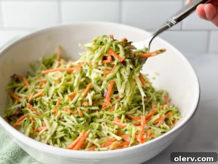 Zesty Broccoli Power Slaw 7 Scooping a portion of creamy broccoli slaw salad into a smaller bowl for individual serving