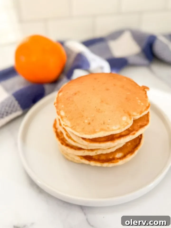 Buttery Fluffy Pancakes 4 Pancakes cooking on a griddle, showing the bubbles forming